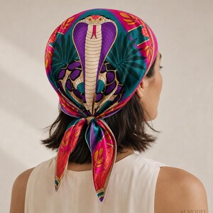May include: A square head scarf tied at the nape of the neck, featuring a vibrant graphic print of a central cobra snake in purple and cream, surrounded by teal palm leaves and bright pink floral patterns with gold accents on a smooth fabric.