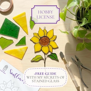 May include: A stained glass sunflower with yellow petals and a brown center, surrounded by green and yellow glass pieces. The image includes tools, a pattern, and text that reads "HOBBY LICENSE" and "+FREE GUIDE WITH MY SECRETS OF STAINED GLASS."