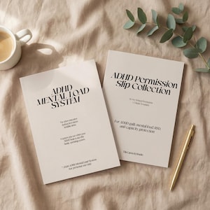 Könnte beinhalten: Zwei beige Bücher mit schwarzem Text, betitelt "ADHD Mental Load System" und "ADHD Permission Slip Collection". Ein goldener Stift liegt neben den Büchern. Eine weiße Tasse mit Kaffee und grüne Blätter sind im Hintergrund.