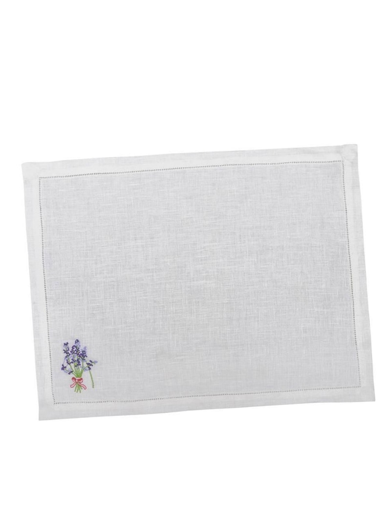 Puede incluir: Mantel individual rectangular blanco con un bordado de ramo de lavanda en la esquina. El mantel individual tiene un borde cosido y est&aacute; hecho de una tela texturizada. El ramo de lavanda presenta flores moradas y una cinta rosa.