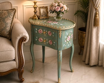 Mesita de noche francesa provenzal con estampado floral en color verde azulado, mesa auxiliar pintada a mano con dos cajones y detalles dorados.