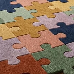 May include: A colorful puzzle-piece rug in shades of blue, green, yellow, orange, and purple. The rug's design features large, interlocking puzzle pieces, creating a playful and inviting floor covering. The rug is made of a soft material.
