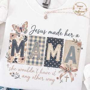 May include: White sweatshirt with the text "Jesus made her a MAMA" in a decorative font. The word "MAMA" is spelled out in individual patches with floral, gingham, and polka dot patterns. A butterfly and floral accents complete the design.