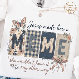 May include: White sweatshirt with the text "Jesus made her a MEME, she wouldn't have it any other way." The word "MEME" is spelled out in decorative patches. A butterfly and floral accents are also featured.