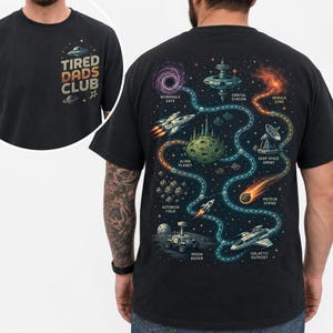 May include: Black t-shirt with a space-themed graphic on the back, featuring a map with planets, spaceships, and the text "Wormhole Gate", "Alien Planet", and "Galactic Outpost". The front of the shirt has the text "TIRED DADS CLUB".