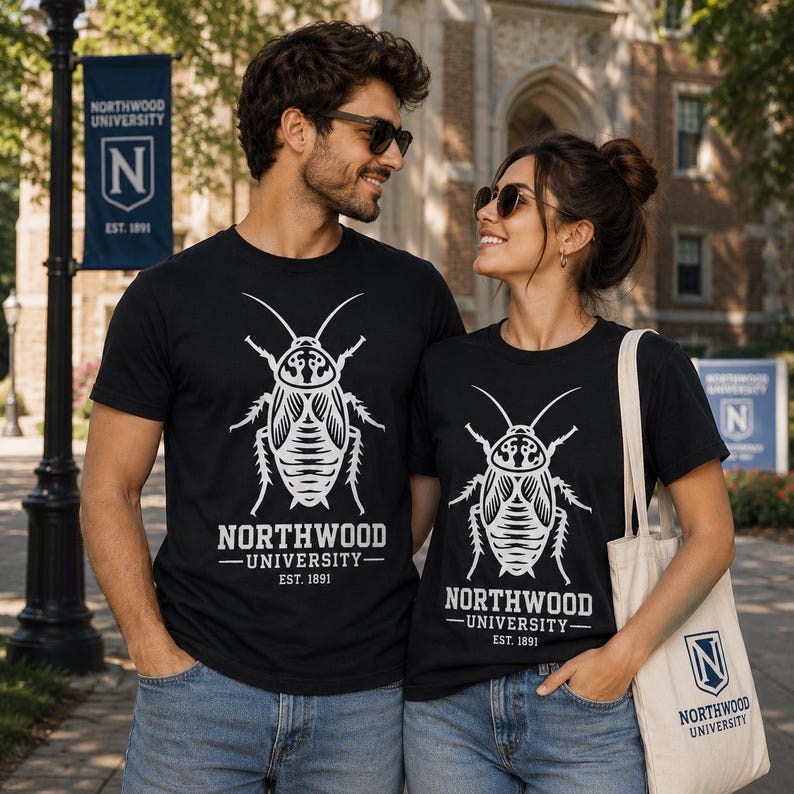 Op de afbeelding: Twee zwarte t-shirts met een witte afbeelding van een kakkerlak boven de tekst Northwood University Est. 1891. Het ontwerp is gecentreerd op de borst van elk shirt. Een beige draagtas met het logo van Northwood University is ook zichtbaar.
