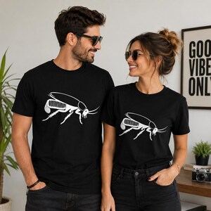 Op de afbeelding: Twee zwarte T-shirts met korte mouwen en een witte grafische print van een kakkerlak op de borst. De shirts hebben een ronde hals en een standaard pasvorm, met een gedetailleerde insectenillustratie in een minimalistische witte lijnstijl.