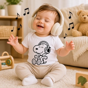 Puede incluir: Un beb&eacute; con auriculares color crema y un body blanco con un gr&aacute;fico negro de Snoopy con auriculares. Notas musicales negras flotan alrededor del beb&eacute;, que sonr&iacute;e. El beb&eacute; est&aacute; sentado en una alfombra color crema.