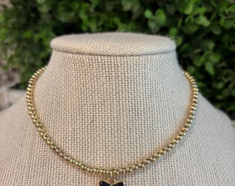 GOLDEN NOIRE “little girl” gold bead necklace with black bow pendant