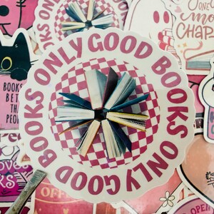 May include: A selection of pink and white stickers with book-related designs. The central sticker says "BOOKS ONLY GOOD BOOKS" around a chequered circle with small book illustrations. Other stickers show a black cat reading and the phrase "Hooked on Books."