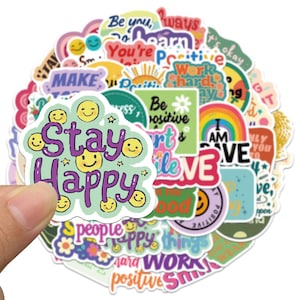 May include: A selection of vibrant stickers with motivational quotes and smiley faces. One sticker says "Stay Happy" in purple, with yellow smiley faces and stars. Other stickers display phrases such as "Be Positive" and "Work Hard".