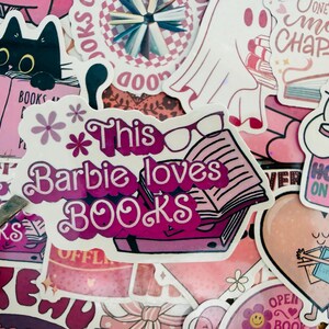 May include: A selection of pink stickers with book-related designs. One sticker says "This Barbie loves BOOKS" with a book and glasses. Other stickers show a black cat reading, a ghost, and the phrase "Hooked on Books."
