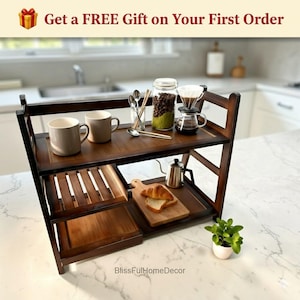 May include: A dark brown, three-tiered wooden kitchen shelf with various coffee-making accessories, mugs, and a small plant. The top shelf holds two mugs, a jar of coffee beans, and a pour-over coffee maker. The text "Get a FREE Gift on Your First Order" is visible.
