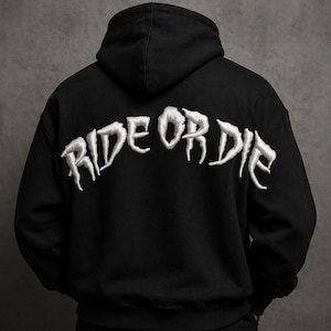 Puede incluir: Sudadera con capucha negra con el texto bordado "RIDE OR DIE" en blanco en la espalda. La sudadera tiene una capucha con cordón y un bolsillo de canguro. La sudadera está hecha de un material suave y cómodo.