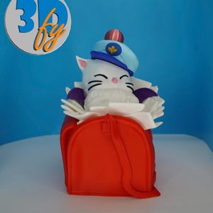 May include: A whimsical, white cat figurine wearing a blue hat with a gold emblem and a pink ball on top. The cat is seated in a red bag with a strap. The image includes a logo with the text "3D by" in blue and orange.