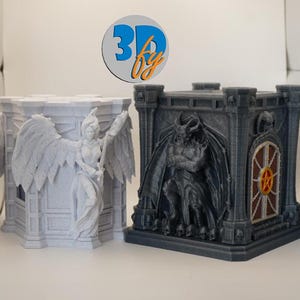 May include: Two detailed 3D-printed sculptures. One is a light gray angel with large wings, holding a sword. The other is a dark gray gothic-style structure with a demon figure and a pentagram design. The logo "3D by" is in the background.