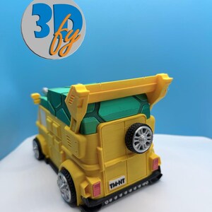 Pode incluir: Uma carrinha de brinquedo amarela e verde com um spoiler e um pneu sobressalente na parte traseira. A carrinha tem rodas pretas e o texto "TM-NT" na parte traseira. A carrinha &eacute; um modelo impresso em 3D.