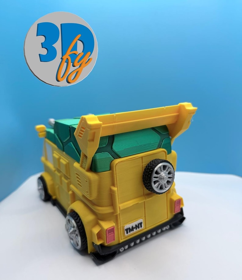 Pode incluir: Uma carrinha de brinquedo amarela e verde com um spoiler e um pneu sobressalente na parte traseira. A carrinha tem rodas pretas e o texto "TM-NT" na parte traseira. A carrinha &eacute; um modelo impresso em 3D.