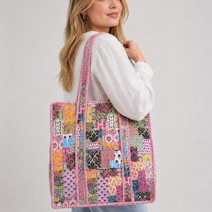 Può includere: Una borsa tote rettangolare caratterizzata da un vivace design patchwork con vari motivi floreali e geometrici nelle tonalità del giallo, rosa, viola e verde. La borsa è dotata di due lunghi manici e rifinita con un bordo a righe rosa e bianco.