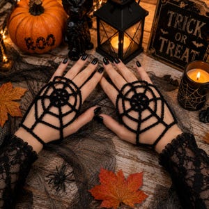 May include: A pair of black crochet fingerless gloves featuring a spider web pattern that covers the back of the hands. The gloves are made of yarn and have a loop for the middle finger to secure the web design in place over the hand.