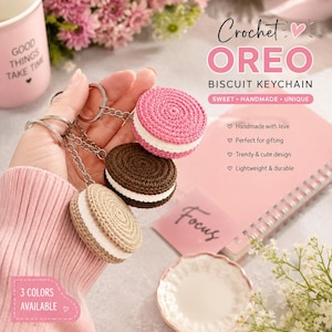 Può includere: Tre portachiavi a forma di biscotto realizzati all'uncinetto in rosa, marrone scuro e beige, ognuno con uno strato centrale bianco e un anello in metallo argentato. Il testo sull'immagine recita Crochet OREO BISCUIT KEYCHAIN, 3 COLORS AVAILABLE e Focus.