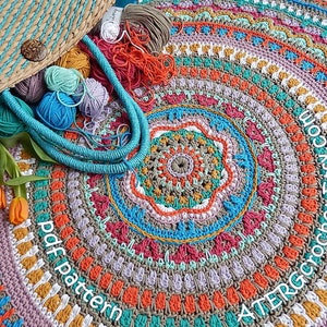 May include: A colorful crochet mandala rug with a variety of colors, including orange, red, pink, blue, green, and yellow. The rug is made with a variety of stitches and patterns, and it has a unique and intricate design. The rug is surrounded by yarn balls and a wicker bag.