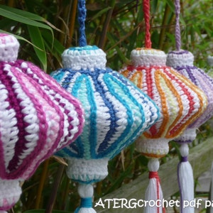 Peut inclure: Cinq ornements suspendus en crochet de différentes couleurs, dont le rose, le bleu, l'orange, le violet et le vert. Chaque ornement a un pompon blanc.