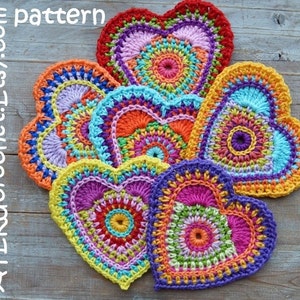 May include: Six colorful crocheted hearts with mandala patterns in shades of pink, orange, yellow, green, blue, and purple. The hearts are arranged in a circle on a wooden surface. The text "ATERcrochet.Etsy.com pattern" is visible in the top left corner of the image.