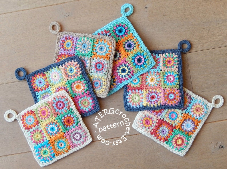May include: Five crocheted pot holders with colorful squares and a loop for hanging. The pot holders are made in various colors including blue, green, orange, pink, yellow, and white. The pot holders are arranged in a semi-circle on a wooden surface. The text 'A TERG crochet pattern Etsy.com' is visible in the bottom center of the image.