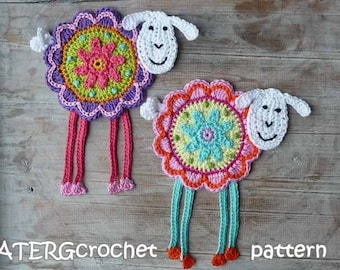 May include: Two crocheted sheep ornaments with colorful flower designs. The sheep are white with black eyes and a black smile. The flowers are pink, green, and blue.