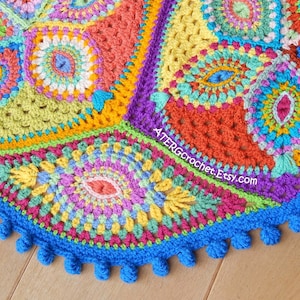 May include: A colorful crocheted round blanket with a blue border and pom-poms. The blanket is made up of different colored squares with intricate patterns.