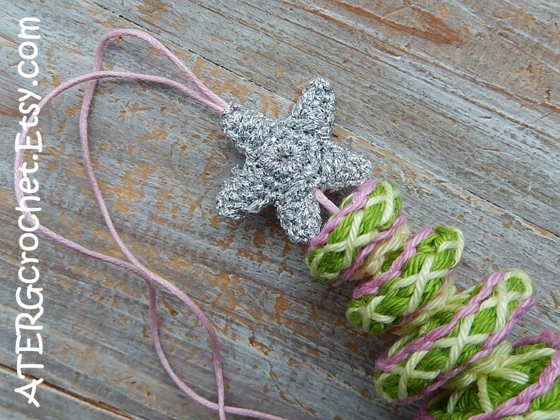 May include: A handmade crochet necklace featuring a silver starfish pendant and a series of green, pink, and white woven rings. The necklace is strung on a pink cord. The text "ATERGcrochet.Etsy.com" is visible.