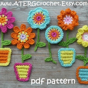 Puede incluir: Un conjunto de siete adornos de maceta de flores de ganchillo en varios colores, incluyendo rosa, naranja, amarillo, azul y verde. Las flores son todas de diseños diferentes y las macetas son todas de formas diferentes. El texto "pdf pattern" está escrito en la superficie de madera debajo de los adornos.