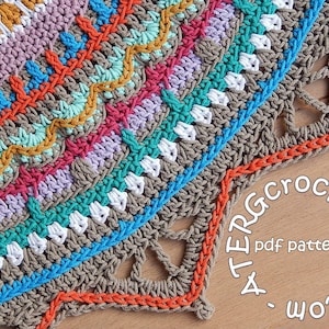 May include: A colorful crochet mandala with a brown center and a scalloped edge. The mandala is made with different colored yarns, including orange, red, pink, purple, blue, green, and yellow. The mandala is on a wooden surface with the text "A TERRA Crochet. Etsy.com pdf pattern" visible.