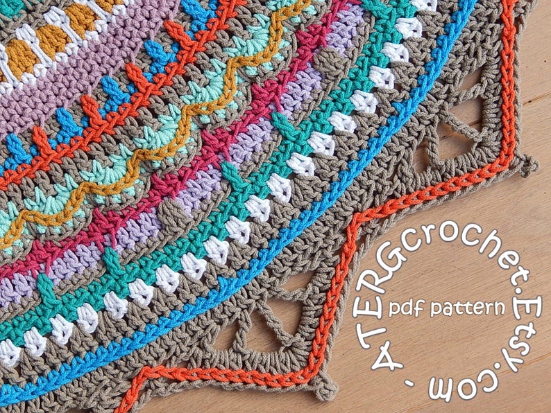 May include: A colorful crochet mandala with a brown center and a scalloped edge. The mandala is made with different colored yarns, including orange, red, pink, purple, blue, green, and yellow. The mandala is on a wooden surface with the text "A TERRA Crochet. Etsy.com pdf pattern" visible.