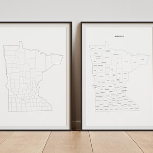 May include: Two framed wall art prints featuring a map of Minnesota. The left print shows the state outline with county borders in black lines on a white background. The right print displays the same map with the text MINNESOTA at the top.