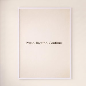 May include: A rectangular wall art print in a thin white frame featuring a cream-colored background with the centered dark brown text "Pause. Breathe. Continue." The design is simple and clean, focusing on the typography displayed on the paper.