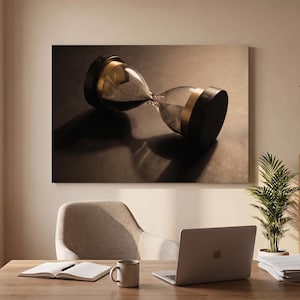 Könnte beinhalten: Ein Wand-Leinwanddruck, der eine horizontale Sanduhr mit dunklem Sand, schwarzen runden Enden und goldfarbenen Akzenten zeigt. Die Sanduhr liegt auf der Seite und wirft einen deutlichen Schatten auf eine dunkle, strukturierte Oberfläche.