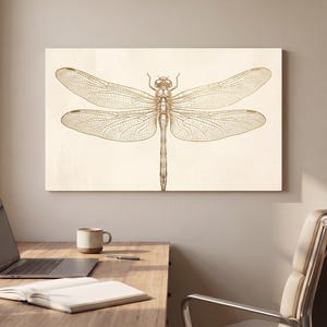 Può includere: Una stampa artistica da parete rettangolare con un'illustrazione dettagliata color oro di una libellula centrata su uno sfondo color crema chiaro. L'insetto è raffigurato con intricate venature alari e un corpo snello, in orientamento orizzontale.