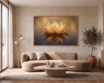May include: A large rectangular wall art print featuring a glowing golden lotus flower floating on dark water with a clear reflection, framed in light wood, displayed above a curved beige sofa and a low wooden coffee table in a room.