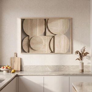 Könnte beinhalten: Ein rechteckiges Wandkunstwerk mit einem hellbeigen Holzrahmen und einer geometrischen Komposition aus überlappenden kreisförmigen und rechteckigen Paneelen in natürlicher Holzmaserung, montiert an einer Wand über einer Küchenarbeitsplatte.