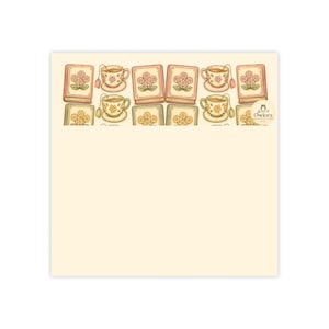 May include: A square cream-colored envelope with a patterned flap featuring a repeating illustration of books and teacups with floral designs. The text "Owlora" is printed in a small circular logo on the right side of the patterned section.