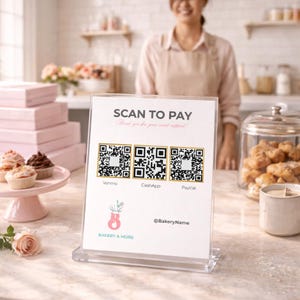 Puede incluir: Un letrero acrílico transparente con el texto "SCAN TO PAY" y códigos QR para Venmo, CashApp y PayPal. El letrero también incluye el texto "Thank you for your sweet support!" y el logotipo y el nombre de la panadería. Cupcakes y cajas rosas en el fondo.