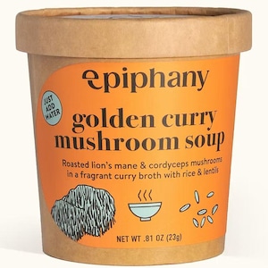 Könnte beinhalten: Ein runder, brauner Papierbehälter mit Epiphany Golden Curry Mushroom Soup. Der Behälter hat ein orangefarbenes Etikett mit schwarzem Text und Illustrationen. Das Etikett lautet "Just Add Water" und "NET WT 23g".