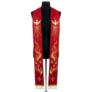 Può includere: Una stola liturgica rossa con ricami dorati. Il design presenta una colomba con linee radianti nella parte superiore e fiamme nella parte inferiore. Croci e frange dorate adornano le estremità. La stola è esposta su un manichino nero.