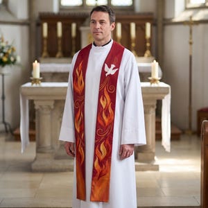 May include: A white liturgical alb worn with a long, deep red stole featuring embroidered orange and yellow flames and a white dove emblem. The stole drapes over the shoulders, extending down the front of the white garment with long panels.
