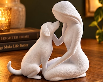 May include: A white, textured sculpture depicting a stylised human figure kneeling and interacting with a dog. The figure has long hair and is leaning forward towards the dog, which is sitting upright with its head tilted towards the figure.