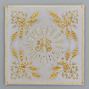 May include: A square light gray fabric pall featuring gold metallic embroidery. The center displays the letters JHS topped with a cross and radiating sunburst rays. Each corner is decorated with gold embroidered wheat stalks and grape vines.