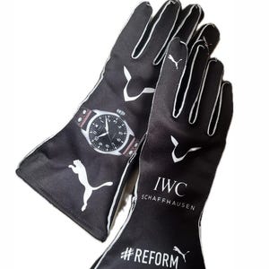 Puede incluir: Par de guantes de carreras negros con detalles blancos y un logotipo de Puma. Un guante presenta un diseño de reloj, el otro tiene impreso "IWC SCHAFFHAUSEN" y "#REFORM".