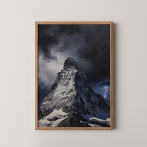 Puede incluir: Una impresión enmarcada que presenta un pico montañoso cubierto de nieve bajo un cielo tormentoso y dramático. La obra de arte muestra la textura accidentada de la montaña y las oscuras nubes arremolinadas, con un relámpago. El marco es de madera clara.